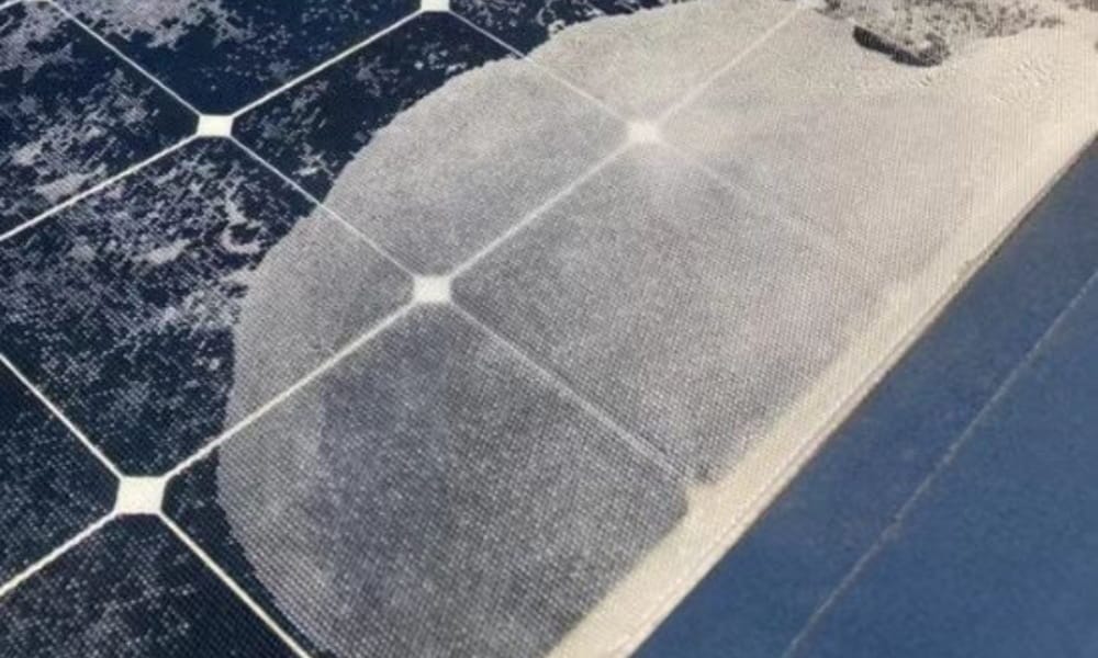 A close-up photo of a flexible solar panel failing due to delamination, with the top plastic layer bubbling and peeling off.