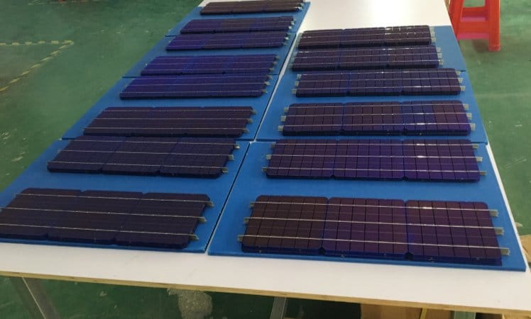 Top-down view of interconnected solar cell strips on a clean circuit board backsheet during the mini solar panel layout process.